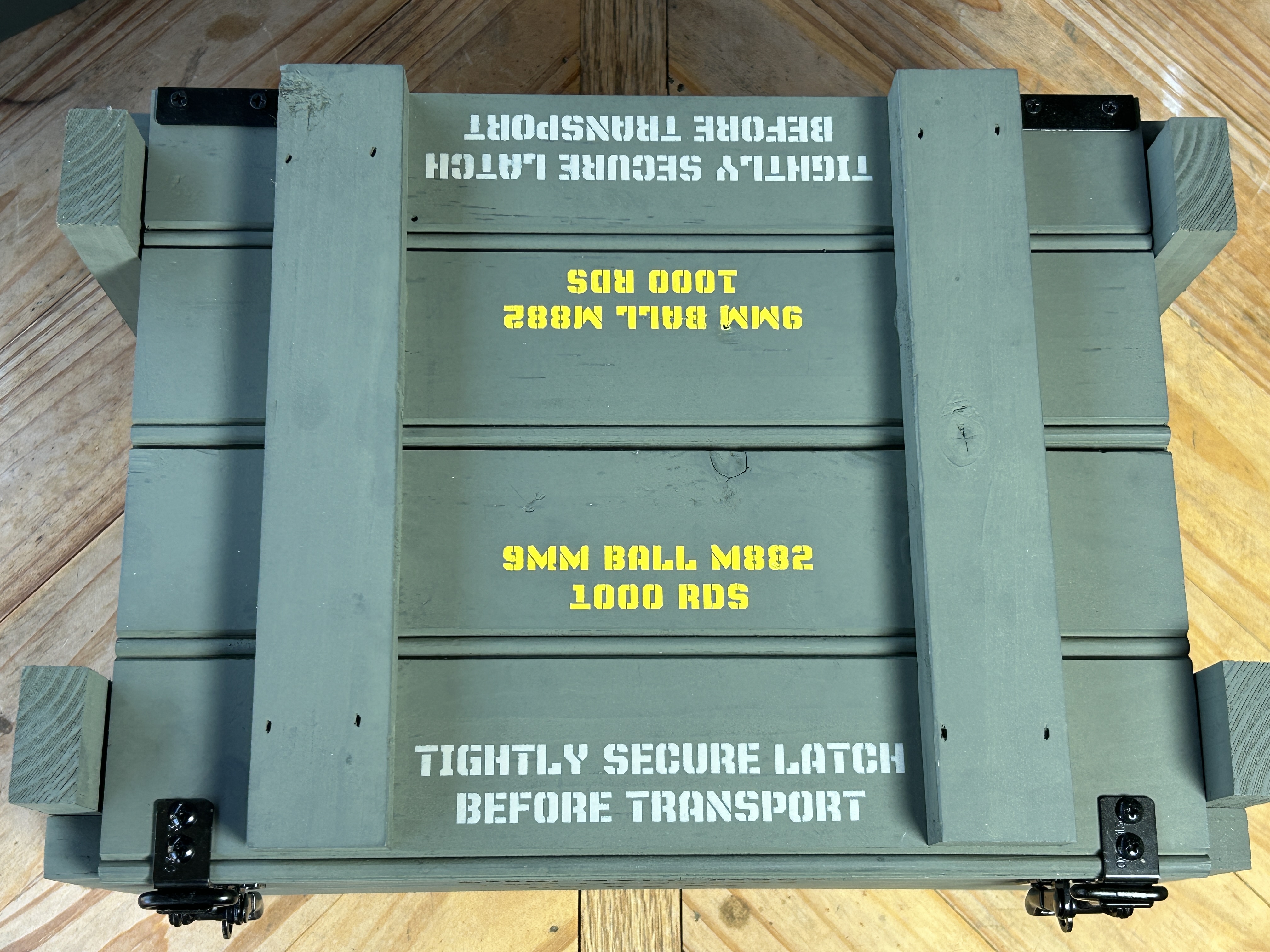 Top-down view of Caliber Collection crate with black hardware and lid stencil text